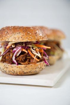 a pulled pork sandwich with coleslaw and carrots on a white plate,