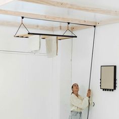 a woman is hanging on the wall with her hands and looking up at something in the air