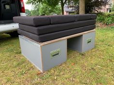 a couch sitting in the back of a truck on top of green grass next to a tree