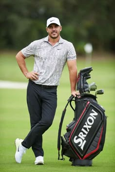 a man standing next to a golf bag on top of a green field