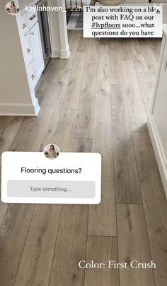 the flooring question is in front of an open kitchen with white cabinets and wood floors