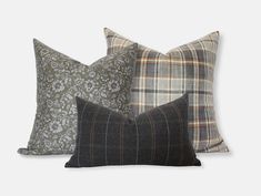 three pillows with different patterns on them, one in grey and the other in brown