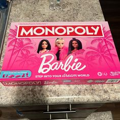 a monopoly board game with barbie dolls on the front and back cover, in a store display case