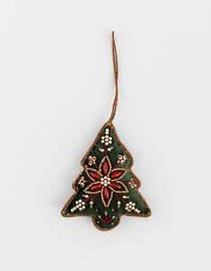 a christmas tree ornament hanging from a string on a white surface with beads