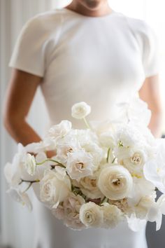 a woman holding a bouquet of white flowers