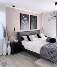 a bedroom with two pictures hanging above the bed