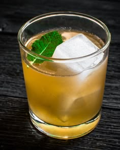 a close up of a drink in a glass on a table with ice and mint