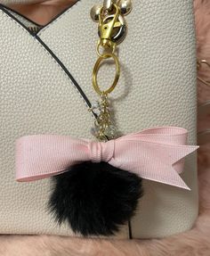 a white purse with a black pom - pom attached to it