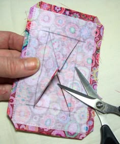 someone is cutting up the end of a small piece of fabric with scissors and thread