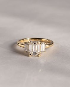 three stone engagement ring in yellow gold with baguettes on the band and side stones