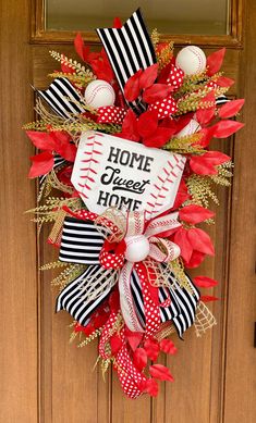 a baseball wreath is hanging on the front door with red, white and black ribbons