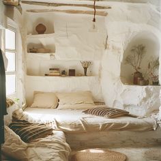 a bed sitting in a bedroom next to a window with lots of pillows on top of it