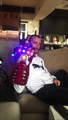 a man sitting on top of a couch holding a light up glove