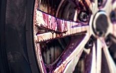 the wheel of a vehicle that is painted purple and red with streaks of paint on it