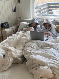 two children are laying in bed on their laptops