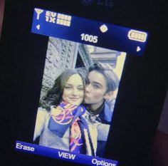 a cell phone with an image of two people on the screen and one is kissing