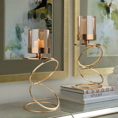 two candles sitting on top of a table next to some books and a vase with flowers