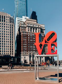 a large red love sculpture sitting in the middle of a city