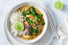 a white plate topped with chicken and rice next to a lime wedge on top of a napkin