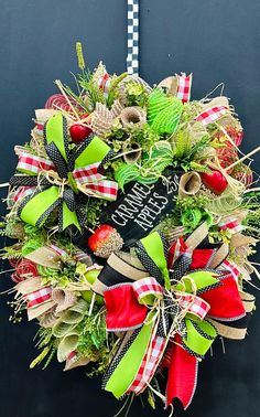 a christmas wreath with green and red bows hanging on the front door for holiday decor