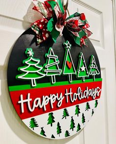 a happy holidays sign hanging on the front door with christmas trees and snowflakes