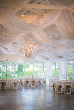 a banquet hall decorated with white draping and chandeliers