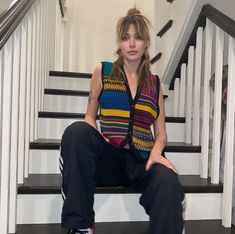 a woman sitting on top of a stair case next to a banister and stairs