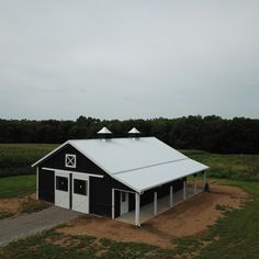 a black and white barn sitting on top of a lush green field