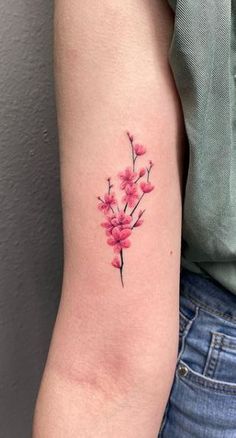 a woman's arm with a pink flower tattoo on the left side of her arm