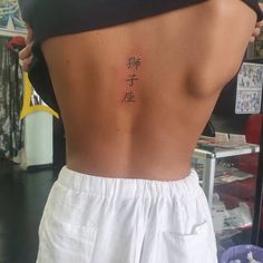 the back of a woman's body with chinese writing on her lower back tattoo