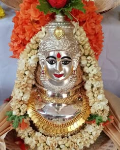 a silver statue sitting on top of a pile of books next to flowers and an orange rose