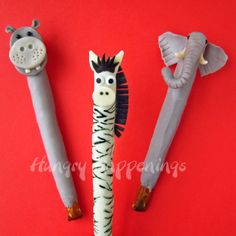 three different animal shaped toothbrushes on a red background