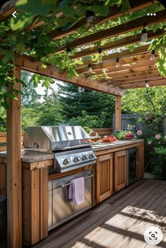 an outdoor kitchen with grill and sink under a pergolated roof, surrounded by greenery