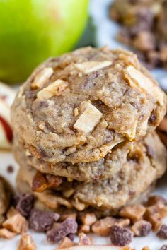 two cookies stacked on top of each other with chocolate chips and apples in the background