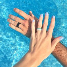 two people holding each other's hands in front of a swimming pool with blue water