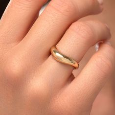 a woman's hand with a gold ring on top of her finger and the other hand holding an object