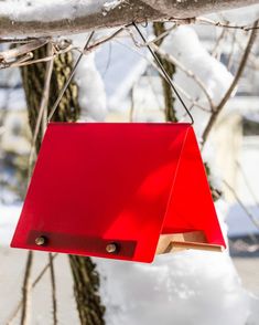 a red bird feeder hanging from a tree