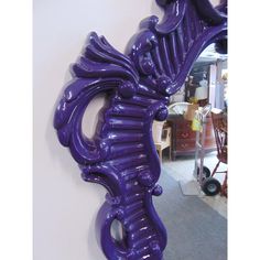 a large purple mirror hanging on the side of a wall