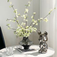 a vase with white flowers sitting on top of a table next to an elephant figurine