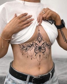 a woman with tattoos on her stomach holding onto the side of her body and looking down