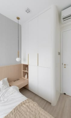 a bedroom with white walls and wooden flooring, an air conditioner hanging from the ceiling