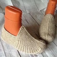 a pair of orange boots sitting on top of a white wooden floor next to a piece of paper