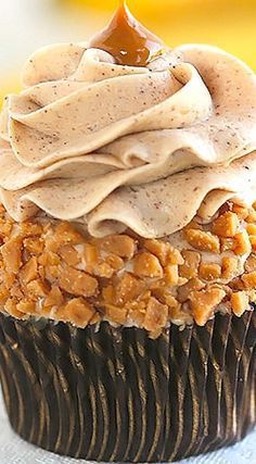 a cupcake with frosting and walnuts on top sitting on a tablecloth