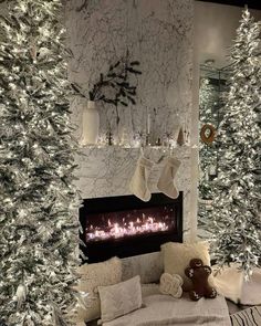 a living room decorated for christmas with white trees and stockings on the fireplace mantel