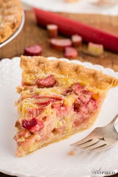 a piece of pie on a white plate with a fork next to it and other food items in the background