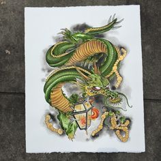 a drawing of a green dragon sitting on top of a piece of paper next to a sidewalk