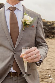 a man in a suit and tie holding a wine glass with a flower on it