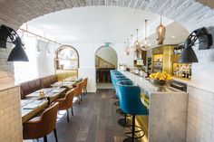 the interior of a restaurant with blue and yellow bar stools, marble counter tops, and wooden flooring