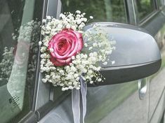 a bouquet of flowers is placed on the side of a car door window as it sits