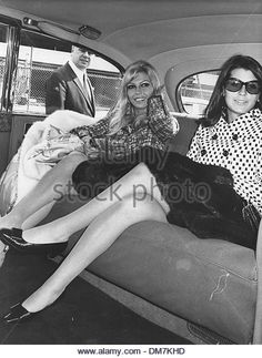 two women sitting in the back seat of a car, one with her legs crossed